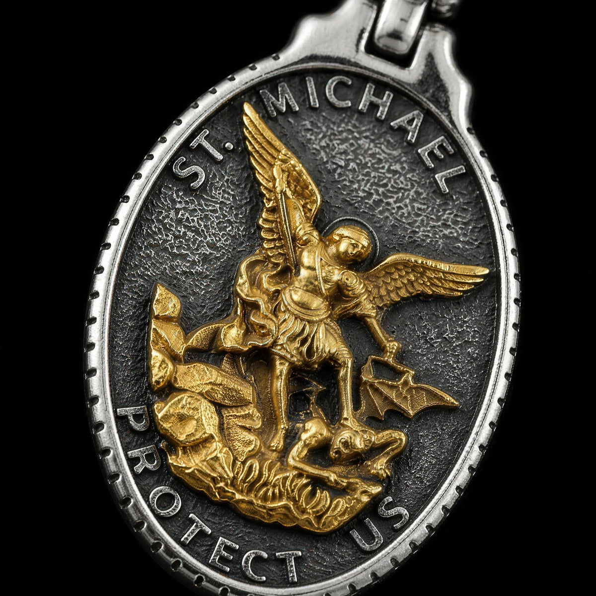 Close-up of the St. Michaels Badge pendant showing the gold Saint Michael relief on oxidised 316L stainless steel