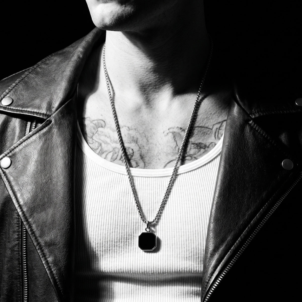Man wearing the The Onyx Badge pendant on a chain, worn on the chest, 316L stainless steel, Outlaws Amsterdam